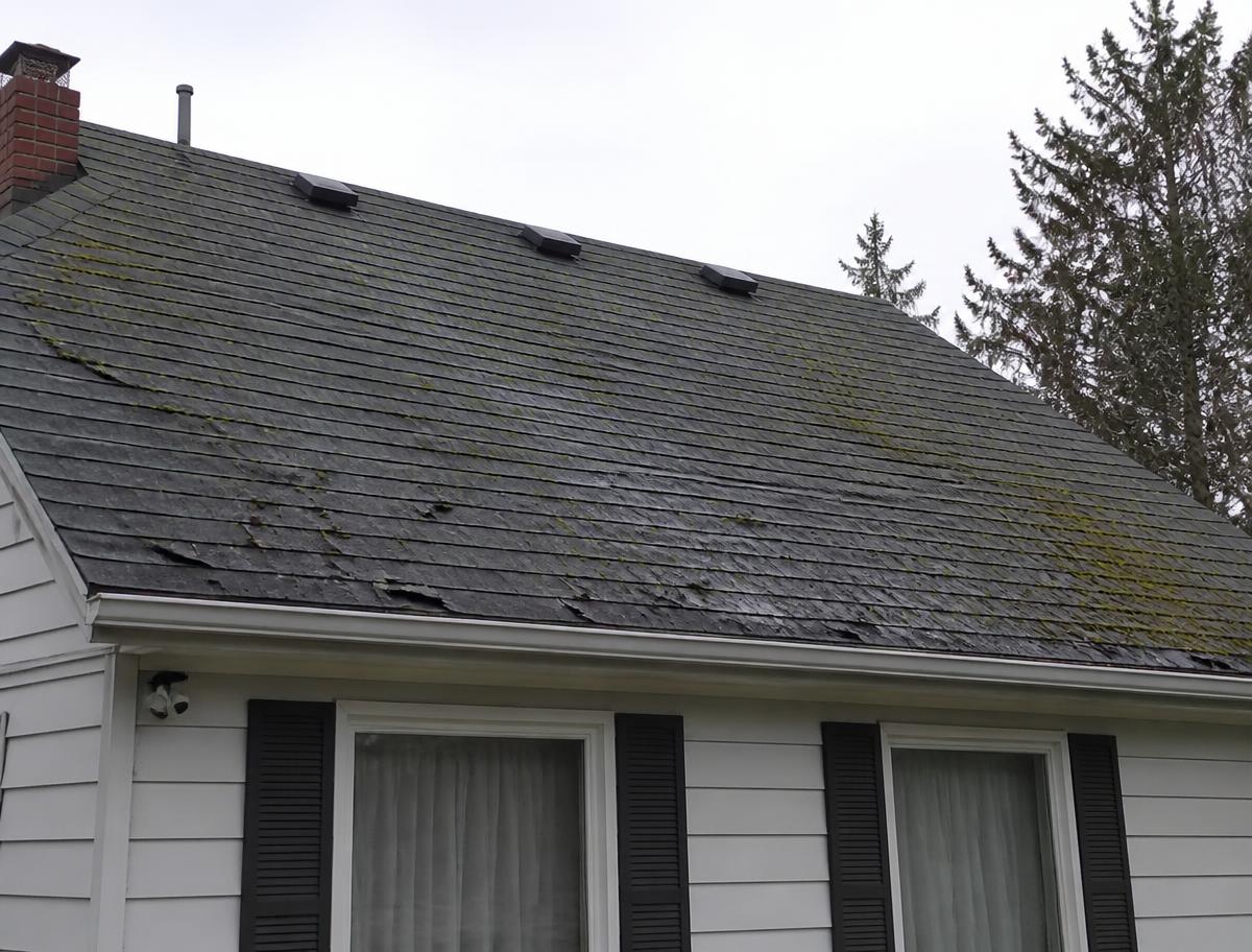 Storm-damaged roof replaced with new architectural shingles; before